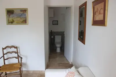 a hallway with a toilet and a couch and a chair at Gîte la Cigale en pleine campagne in Carpentras