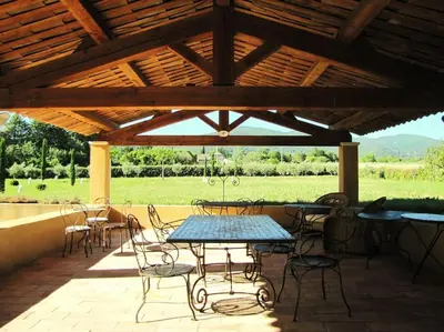 a patio with tables and chairs under a wooden roof at LUBERON - AIR CONDITIONING VILLA - 4 BEDROOMS - 4 BATHROOM in Lourmarin