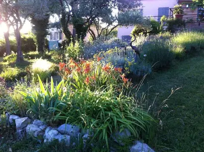 a garden with flowers and rocks in a yard at Les Merles : joli studio dans la campagne Aixoise. in Venelles