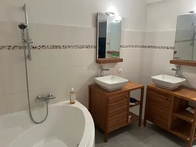 a bathroom with a tub and two sinks and a shower at Appartement privatif avec extérieur in Aubignan