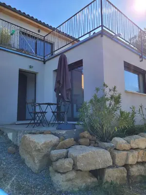 a house with a balcony and a table and some rocks at Gîte au pied du mont ventoux in Bédoin