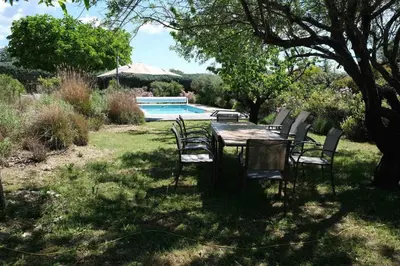 a table and chairs in a yard with a pool at Air-conditioned house in the Luberon with heated swimming pool in Saint Saturnin les Apt - 8 people. in Saint-Saturnin-les-Apt