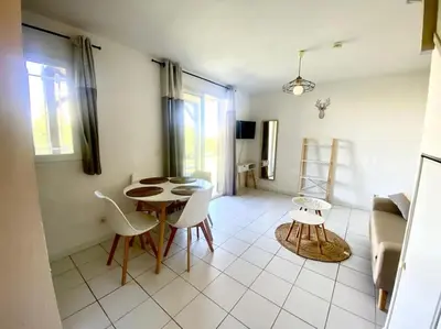 a living room with a table and chairs in a room at T2 Résidence Sun Hols les Rives du Lac piscine, jardin in Saint-Saturnin-lès-Avignon