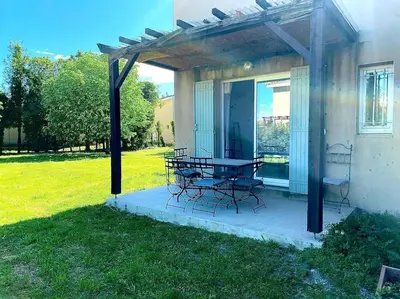 a patio with a table and chairs under a pergola at T2 Résidence Sun Hols les Rives du Lac piscine, jardin in Saint-Saturnin-lès-Avignon