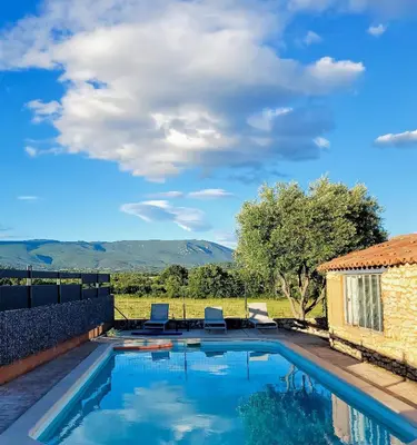a swimming pool with two chairs and mountains in the background at Gîte de charme avec Piscine dans le Luberon au Domaine Artemiss in Apt