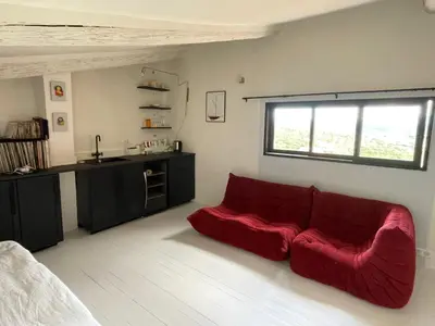 a living room with a red couch and a kitchen at La Farigoulette - Vieux village in Saint-Saturnin-les-Apt
