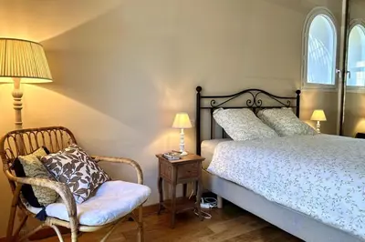 a bedroom with a bed and a chair and a lamp at Les Lauriers Roses air-conditioned villa with garden and swimming pool in Saumane-de-Vaucluse