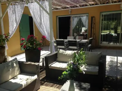 a patio with wicker furniture and a table and chairs at Villa provençale entre Aix en Provence et Luberon in Rognes
