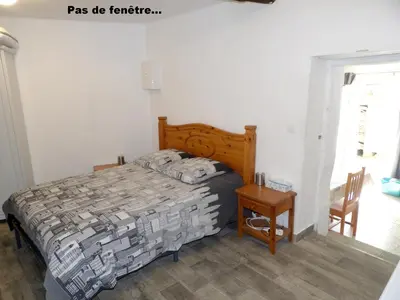a bedroom with a bed and a table and a window at Studio chez Steph in Eyguières
