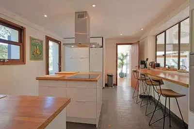 a kitchen with white cabinets and a counter with stools at Grande villa avec piscine près d'Avignon - Jonquerettes in Jonquerettes