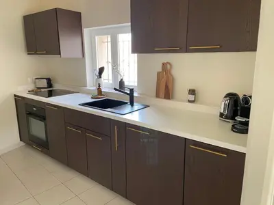 a kitchen with brown cabinets and a sink at UN DOUX MOMENT in Pernes-les-Fontaines