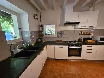 a kitchen with white cabinets and black counter tops at Maison à Ansouis Luberon in Ansouis
