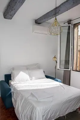 a white bed with a blue chair in a room at Cosy apartment Right in Cours Mirabeau in Aix-en-Provence