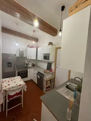 a kitchen with white cabinets and a table in it at Cosy apartment Right in Cours Mirabeau in Aix-en-Provence