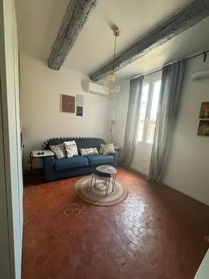a living room with a blue couch and a table at Cosy apartment Right in Cours Mirabeau in Aix-en-Provence