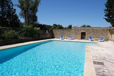 a swimming pool with chairs and a house at Provencal Farm with swimming pool near Isle sur la Sorgue - 10 people. in Les Vignères