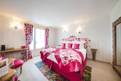 a bedroom with a pink bed and a window at Le Palais d'Aglaé, Hôtel de Charme in Gordes
