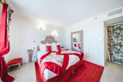 a bedroom with a red and white bed and a mirror at Le Palais d'Aglaé, Hôtel de Charme in Gordes