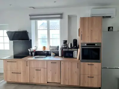 a kitchen with wooden cabinets and a sink and a refrigerator at Appartement Au Murmure des Eaux à Fontaine-de-Vaucluse in Fontaine-de-Vaucluse