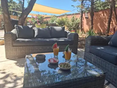 a patio with a couch and a table with drinks on it at Location indépendante au cœur des Alpilles pour 2 personnes avec Jacuzzi in Aureille