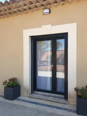 a black door on the side of a building at Location indépendante au cœur des Alpilles pour 2 personnes avec Jacuzzi in Aureille