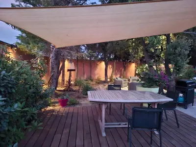 a wooden patio with a table and chairs under a pavilion at Location indépendante au cœur des Alpilles pour 2 personnes avec Jacuzzi in Aureille