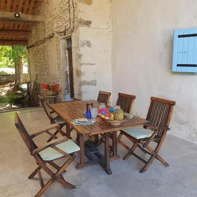 a wooden table with chairs and a bowl of fruit on it at La Grange des Davids Mas en Provence in Oppedette