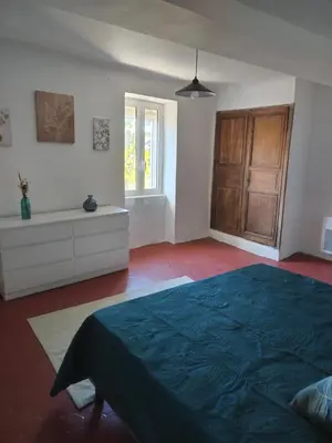 a bedroom with a bed and a dresser and a window at Maison dans le luberon in Viens
