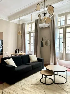 a living room with a black couch and a table at Splendide T2 au coeur d'Aix et du Cours Mirabeau in Aix-en-Provence