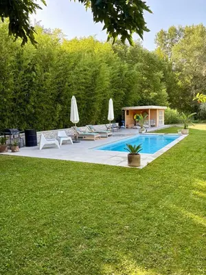 a swimming pool in a yard with chairs and umbrellas at Maison avec piscine au calme au pied du Ventoux in Mazan