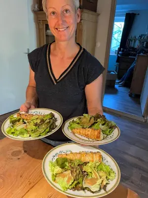 a woman sitting at a table with four plates of food at 