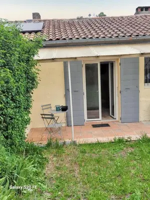 a house with a table and a chair on a patio at Maison charmante à Saint-Michel-l'Observatoire avec jardin in Saint-Michel-lʼObservatoire