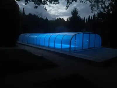 a building with blue lights in the dark at Le Coin Retro pour séjour romantique avec piscine chauffée in Le Thor