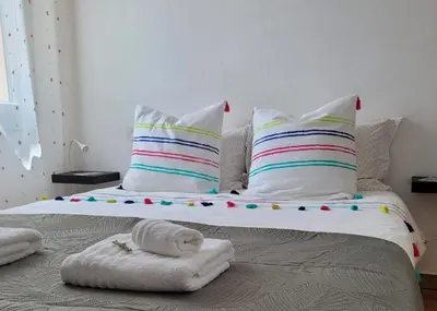 a large bed with colorful pillows and a blanket at Le jardin des oliviers in Apt