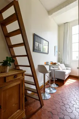 a staircase in a living room with a table and a couch at Cocon provençal dans le centre historique in Aix-en-Provence