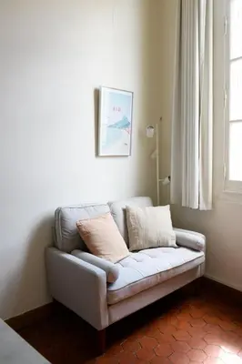 a couch sitting in a living room with a window at Cocon provençal dans le centre historique in Aix-en-Provence