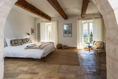 a bedroom with a large bed and two windows at Vue Dexception Gordes in Gordes