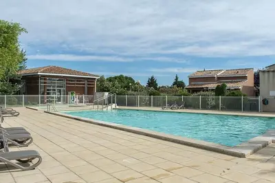 a large swimming pool with chairs and a building at La provençale in Saint-Saturnin-lès-Avignon
