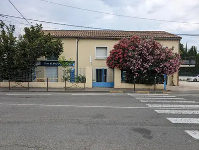 a building with a flowering tree on the side of a street at L'instant sorgue in LʼIsle-sur-la-Sorgue