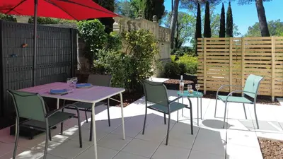 a patio with a table and chairs and an umbrella at Au calme dans la campagne Aixoise, entouré de cyprès in Aix-en-Provence