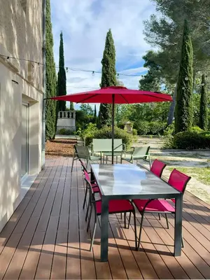a table and chairs with a red umbrella on a patio at Au calme dans la campagne Aixoise, entouré de cyprès in Aix-en-Provence