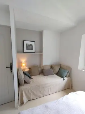 a white bedroom with a bed with a lamp on it at Le Petit Paradis in Saint-Martin-de-Castillon
