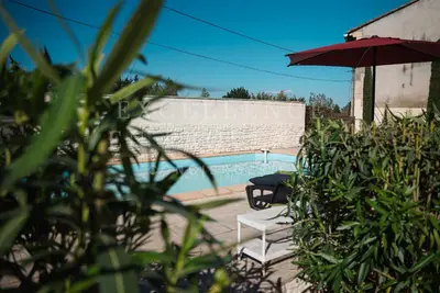 a pool with a table and an umbrella and a bench at Mas de l'air in Noves