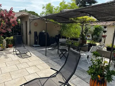 a patio with chairs and a table in a backyard at Le refuge des oiseaux in Lourmarin