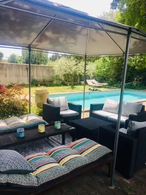 a gazebo with chairs and a table next to a pool at Maison provençale avec piscine in Loriol-du-Comtat