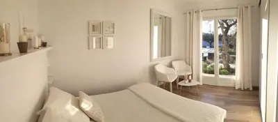 a white bedroom with a bed and a window at Le Cabanon de Marie in Saignon