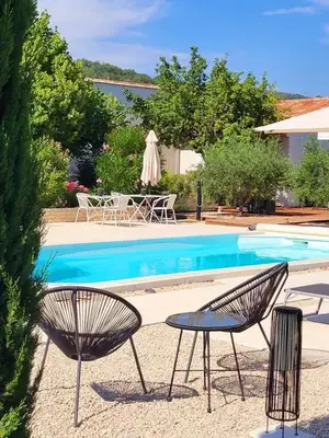 a pool with two chairs and a table and an umbrella at Le Cabanon de Marie in Saignon