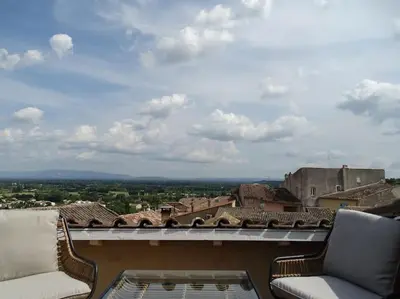 a balcony with two chairs and a view of a city at Maison avec terrasse panoramique in Châteauneuf-de-Gadagne