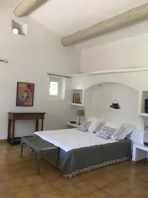 a bedroom with a bed and a table in it at L'Atelier de la Baronnie - Lubéron in Cabrières-dʼAvignon
