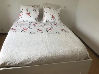 a bed with white sheets and red birds on it at Ayoug Chambre Individuelle Chez Habitat in Carpentras